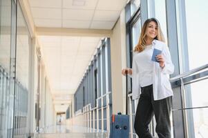 joven bonito elegante mujer con equipaje a el internacional aeropuerto. esperando su vuelo a impuesto gratis compras zona. foto