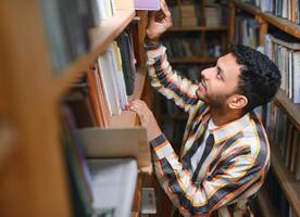 Happy smart indian or arabian guy, mixed race male, university student, in the library photo