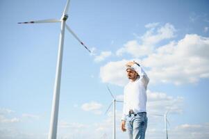 ingeniero India hombre trabajando a molino granja generando electricidad limpiar energía. viento turbina granja generador por alternativa verde energía. asiático ingeniero comprobación controlar eléctrico poder foto