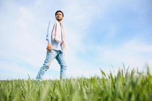 Portrait of farmer standing in a wheat field. farmer stands in green wheat field, looks, examines his crop photo