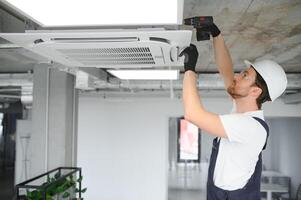 Happy Male Technician Repairing Air Conditioner photo