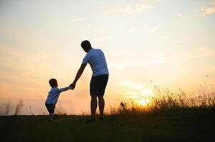 Young father throws up his cute and little son in the fresh air. Father's Day, Father and his son baby boy playing and hugging outdoors. photo