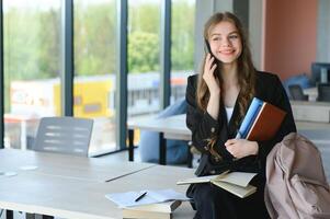 Portrait of a schoolgirl standing in the classroom with a book in her hands. photo