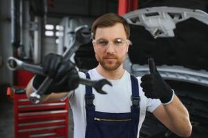 con herramienta en mano. adulto hombre en de colores uniforme trabajos en el automóvil salón foto