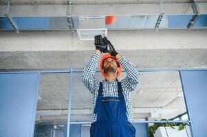 hvac indian worker install ducted pipe system for ventilation and air conditioning. copy space photo