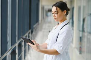 Portrait of young female doctor standing in hospital corridor. Caucasian woman working in nursing home. photo