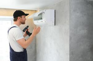 Male technician repairing air conditioner indoors photo