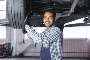 service, repair and profession concept - indian mechanic at car service photo