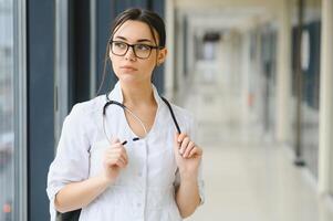 Happy young female doctor wear uniform, white medical coat, stethoscope. Portrait of beautiful female doctor, therapist, nurse. photo