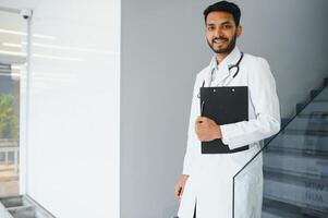 medicine, healthcare and people concept - happy male doctor with stethoscope and clipboard at clinic photo