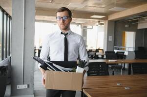 business, firing and job loss concept - fired male office worker with box of his personal stuff. photo