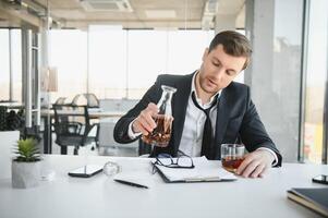 Businessman drinking from stress at workplace photo