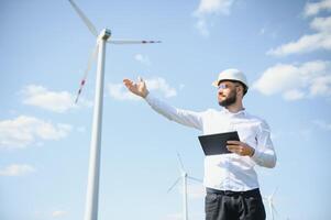 Male engineer working with plan inspecting or maintenance of wind turbines at windmill field farm. photo