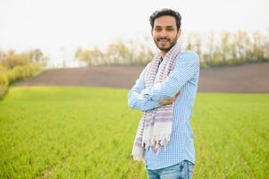 Portrait of young Indian Farmer wearing formal dress in green paddy field. photo