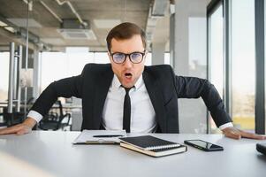 Angry businessman sitting at the table and screaming. photo