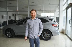 un hombre elige un nuevo coche para él mismo camina Entre el filas en un coche concesión foto