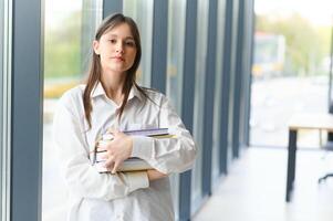 Portrait of a schoolgirl at school. She holds books in her hands. Education concept. photo