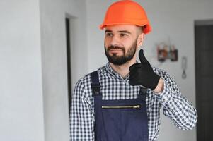 Portrait of positive, handsome young male builder in hard hat photo