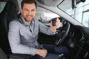 Young man is choosing a new vehicle in car dealership. photo