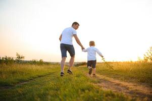 joven padre lanza arriba su linda y pequeño hijo en el Fresco aire. del padre día, padre y su hijo bebé chico jugando y abrazando al aire libre. foto