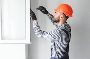 Worker in installing white plastic upvc window on house. photo