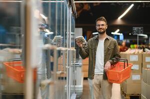 A handsome young man in a grocery store chooses food products. photo