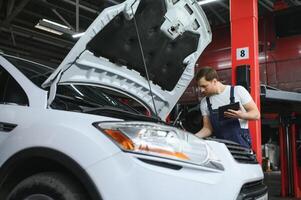 Automobile computer diagnosis. Car mechanic repairer looks for engine failure on diagnostics equipment in vehicle service workshop photo