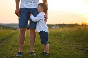 del padre día. contento familia padre y niñito hijo jugando y riendo en naturaleza a puesta de sol foto