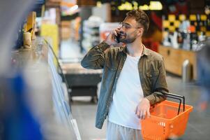 Handsome young man choosing food in the supermarket. photo