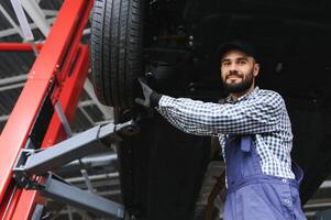 Portrait of a mechanic repairing a lifted car photo