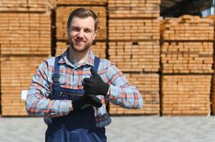 Carpenter in uniform check boards on sawmill photo