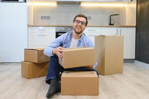 moving, people and real estate concept - happy smiling man with boxes at new home photo