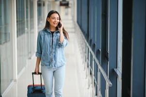 Young woman pulling suitcase in airport terminal. Copy space photo