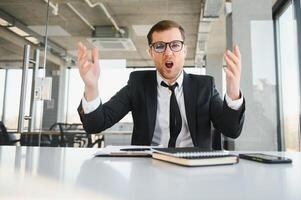 Angry senior businessman sitting at his desk and screaming photo