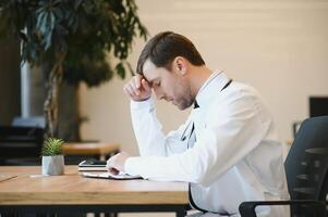 Young man wearing doctor uniform stressed working at clinic photo