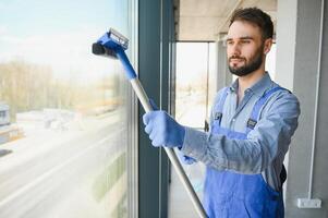 Young man cleaning window in office photo