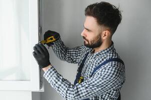 Worker in installing white plastic upvc window on house. photo