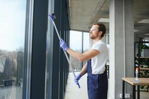 An employee of a professional cleaning service washes the glass of the windows of the building. Showcase cleaning for shops and businesses. photo