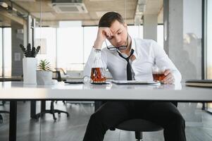 Businessman drinking from stress at workplace photo