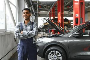 latin hispanic auto mechanic in uniform is examining a car while working in auto service photo