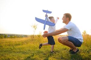 papá con su hijo a puesta de sol en naturaleza. un padre obras de teatro con juguete aviones con su hijo a puesta de sol. del padre día foto