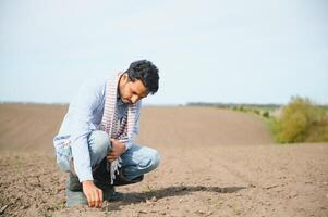 un joven indio granjero inspecciona su campo antes de siembra. foto