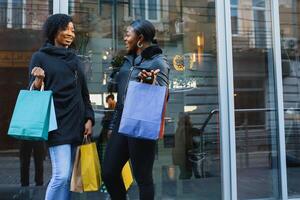 joven negro mujer yendo compras. africano americano muchachas con compras pantalones Vamos compras foto