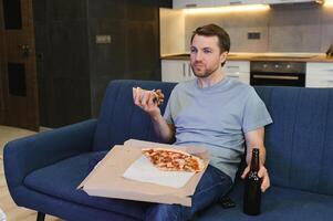 Man eating pizza having a takeaway at home relaxing resting photo
