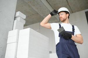 retrato de positivo, hermoso joven masculino constructor en difícil sombrero. foto