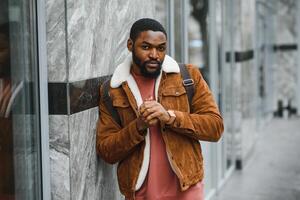 portrait of confident trendy serious african guy in stylish outfit, young afro american male posing at camera, looking away photo