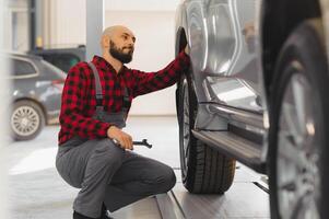 The hand of a car mechanic with a wrench in a combi zone near the car in the workshop photo