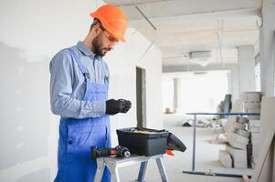 building, protective gear and people concept - builder carrying toolbox at construction site photo