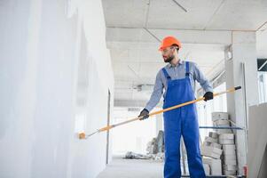 Painter in uniform paints the wall. photo