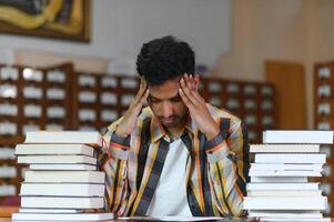 masculino indio estudiante a el biblioteca con libro foto
